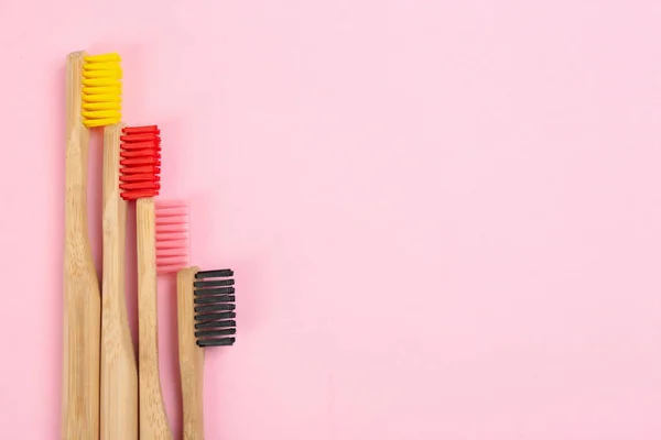 Zahnbürsten aus Bambus auf rosa Hintergrund, flach gelegt. Raum — Stockfoto