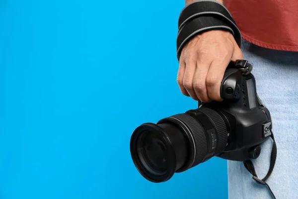 Professioneller Fotograf mit moderner Kamera auf hellblauem Backg — Stockfoto