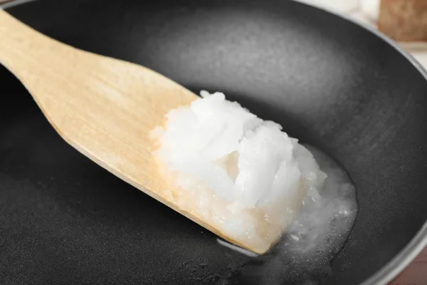 Frying pan with coconut oil and wooden spatula, closeup. Healthy — Stock Photo, Image