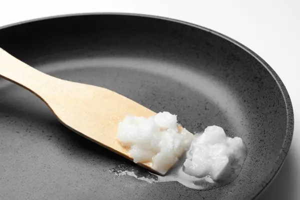 Τηγάνι τηγανίσματος με λάδι καρύδας και ξύλινη σπάτουλα σε λευκό backgrou — Φωτογραφία Αρχείου