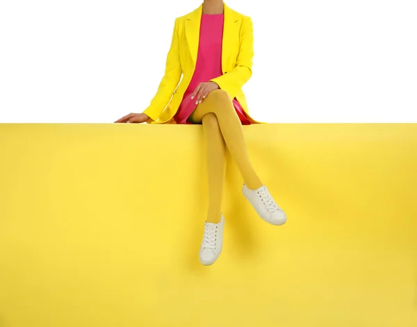 Woman wearing yellow tights and stylish shoes sitting on color b — Stock Photo, Image