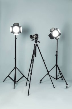 Gri arkaplanda profesyonel video kamera ve aydınlatma ekipmanları