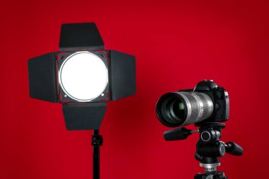 Kırmızı arkaplanda profesyonel video kamera ve ışıklandırma ekipmanları