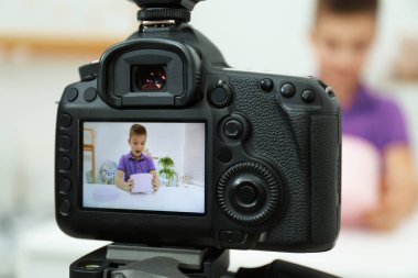 Emotional little blogger with box recording video at home, focus on camera clipart