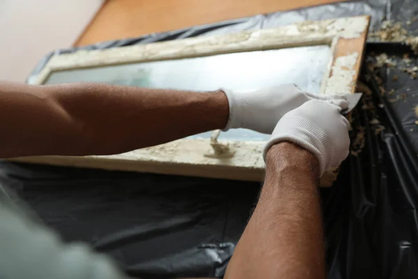 Человек ремонтирует старое поврежденное окно за столом, крупным планом — стоковое фото