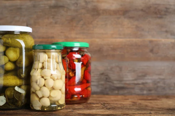Glass jars with different pickled vegetables on wooden table. Sp — Stock Photo, Image