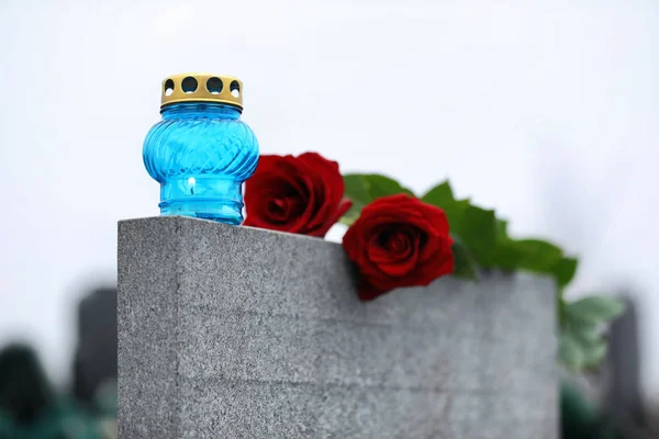 Red roses and candle on light grey tombstone outdoors. Funeral c — 스톡 사진