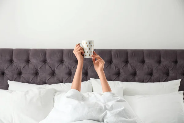 Kobieta z filiżanką kawy w łóżku, zbliżenie. Leniwy poranek — Zdjęcie stockowe