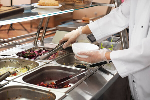 School canteen worker at serving line, closeup. Tasty food