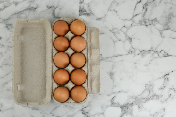 Raw chicken eggs on white marble table, top view. Space for text