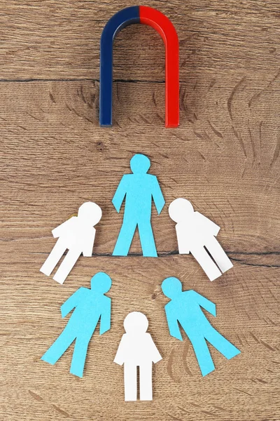 Magnet and paper people on wooden table, flat lay