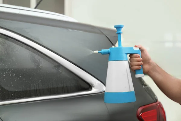 Trabajador rociando agua en la ventana del coche antes de teñir en el taller —  Fotos de Stock