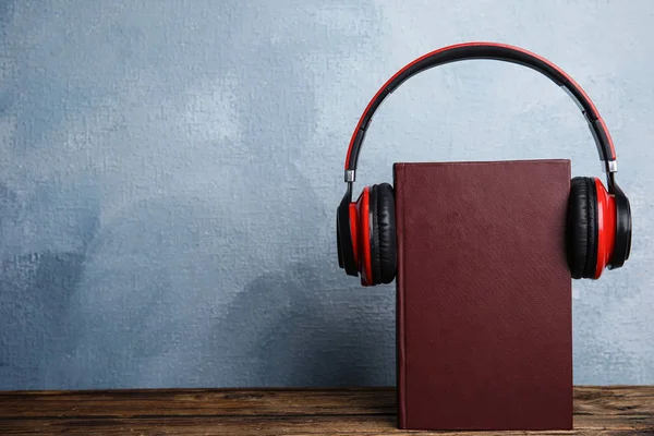 Libro y auriculares modernos en mesa de madera. Espacio para texto — Foto de Stock