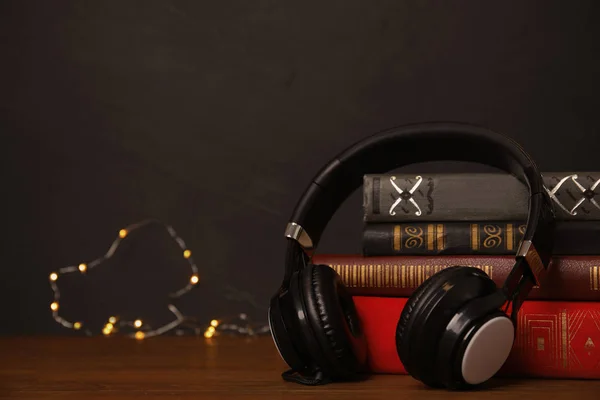 Livres et écouteurs sur table en bois sur fond noir. S — Photo