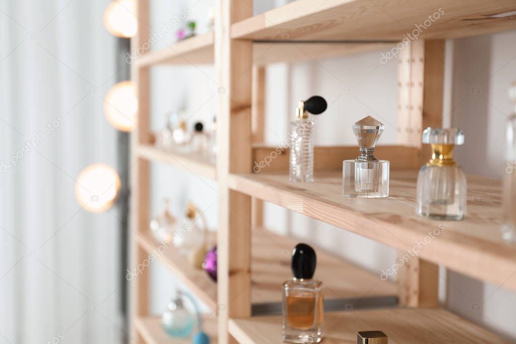 Different perfume bottles on wooden rack indoors