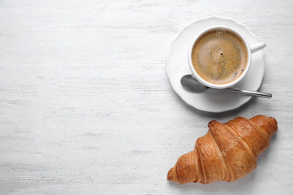 Tasty croissant and coffee on white wooden table, flat lay. Space for text