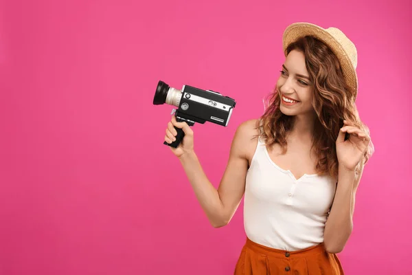 Mooie jonge vrouw met vintage video camera op crimson backg — Stockfoto