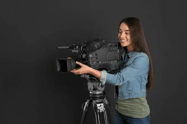 Operator with professional video camera on black background