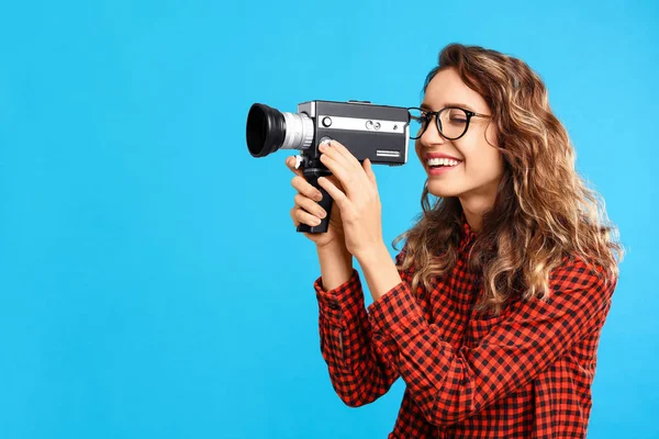 Mooie jonge vrouw met vintage video camera op licht blauw ba — Stockfoto