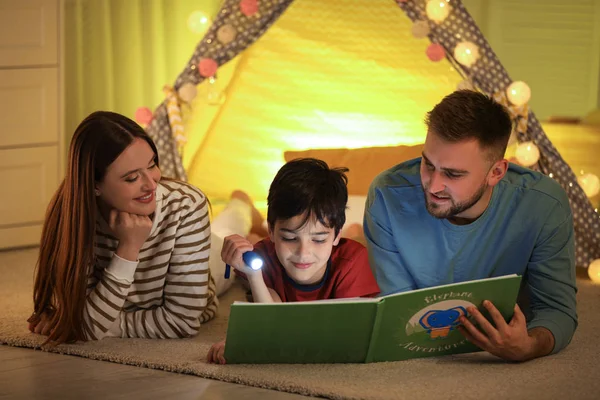 Rodina s baterkou čtení knihy doma — Stock fotografie
