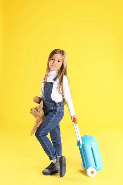 Cute little girl z walizką na żółtym tle — Zdjęcie stockowe