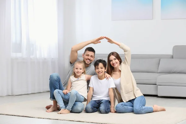 Família feliz formando telhado casa com as mãos em casa. Insura — Fotografia de Stock