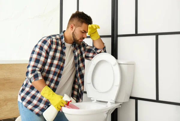 Joven sensación de disgusto al limpiar el inodoro en el baño — Foto de Stock