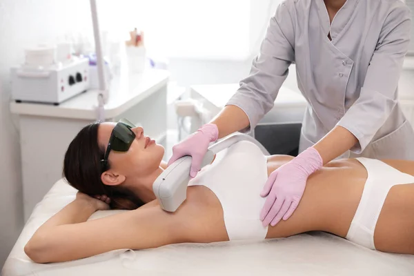 Młoda kobieta w trakcie procedury depilacji laserowej w salonie piękności — Zdjęcie stockowe