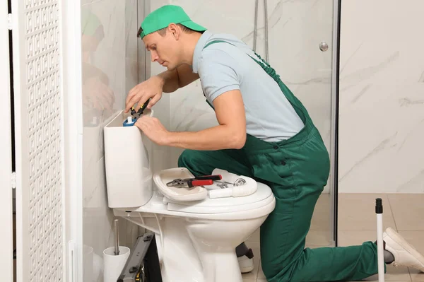 Professional plumber repairing toilet tank in bathroom — Stock Photo, Image