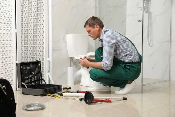 Fontanero profesional reparando inodoro en el baño —  Fotos de Stock