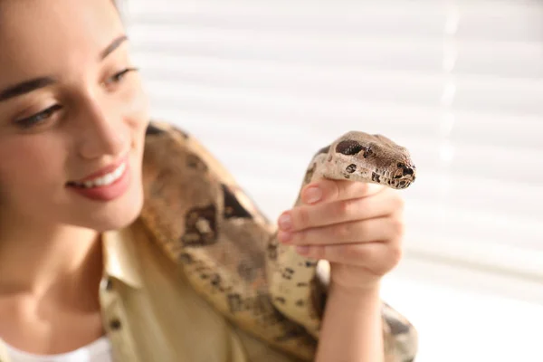 Young woman with her boa constrictor at home, closeup. Exotic pe