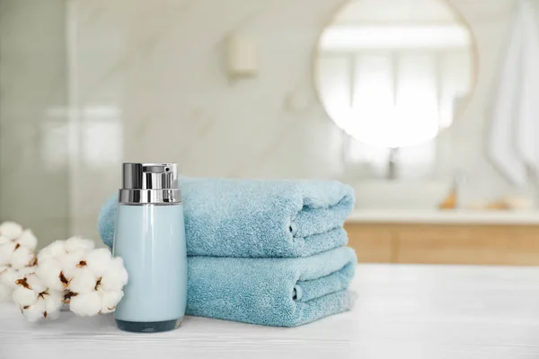 Clean towels, cotton flowers and soap dispenser on white wooden — Stock Photo, Image