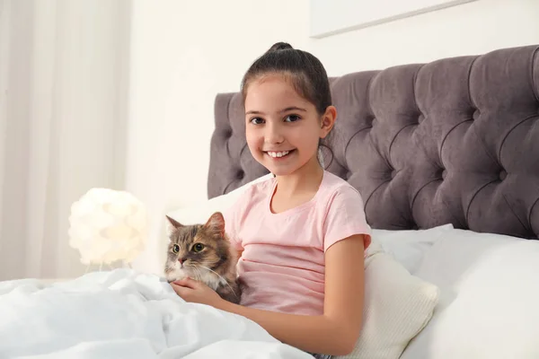 Menina bonito com gato deitado na cama em casa. Primeiro animal — Fotografia de Stock