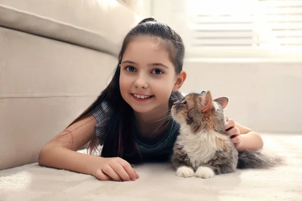 Nettes kleines Mädchen mit Katze, die zu Hause auf Teppich liegt. erstes Haustier — Stockfoto