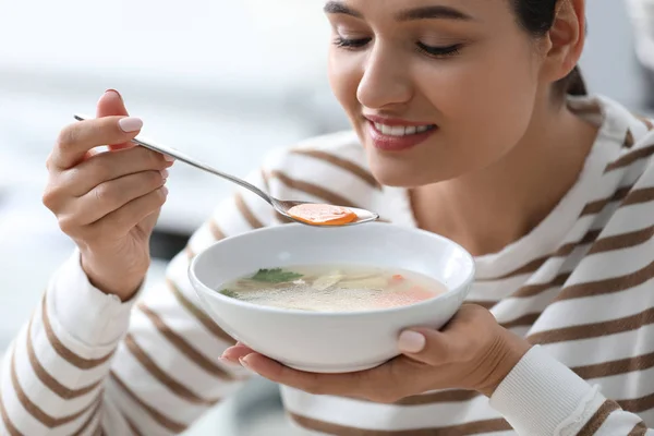 Молодая женщина ест вкусный овощной суп в помещении — стоковое фото