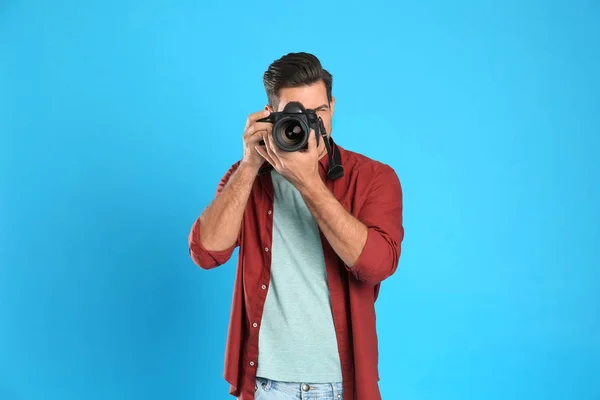 Profesionální fotograf pracující na světle modrém pozadí v st — Stock fotografie