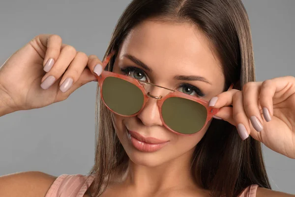 Piękna Młoda Kobieta Okularach Przeciwsłonecznych Szarym Tle Zbliżenie — Zdjęcie stockowe