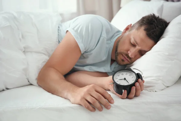 Man sleeping with alarm clock at home in morning — Stockfoto