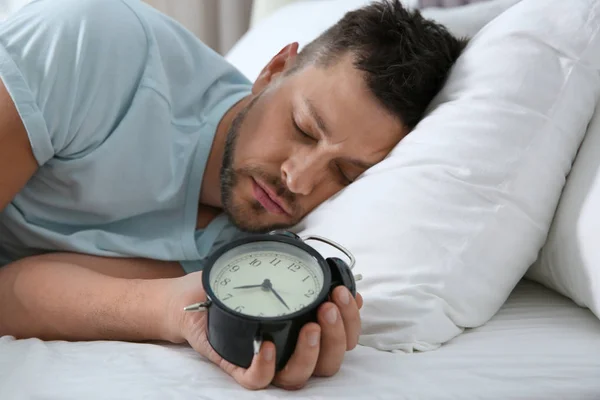 Man sleeping with alarm clock at home in morning — Stockfoto