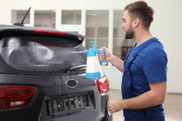 Worker spraying water onto car window before tinting — 스톡 사진
