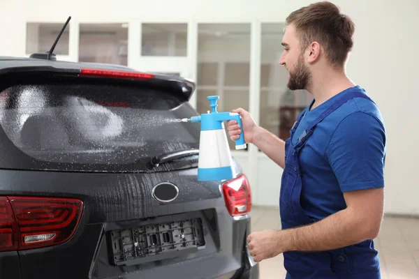 Arbetstagaren sprutar vatten på bilfönstret innan färgning — Stockfoto