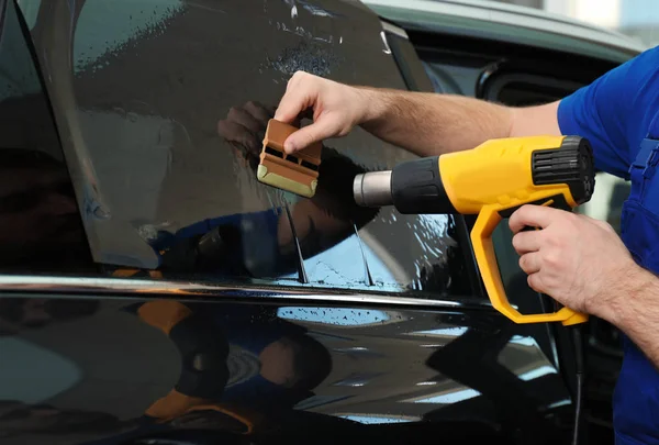 Obrero teñido ventana del coche con pistola de calor en el taller, primer plano — Foto de Stock