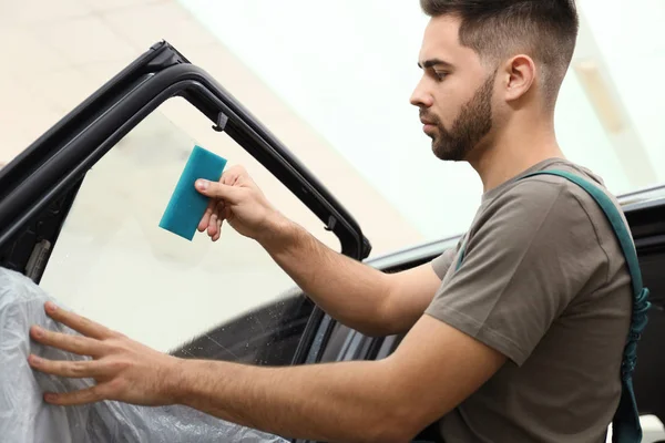 Trabajador lavado ventana de coche teñido en el taller — Foto de Stock