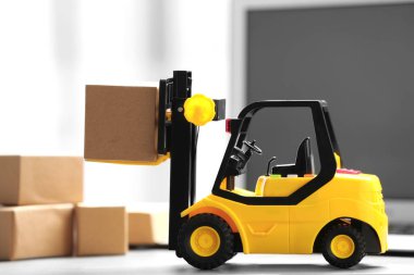 Oyuncak forklift, masadaki dizüstü bilgisayarın yanında. Lojistik ve toptan satış kavramı