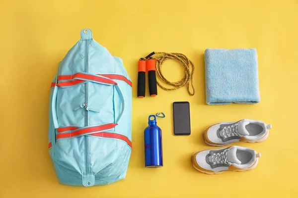 Gym bag, smartphone and sports equipment on yellow background, f — Stock Photo, Image