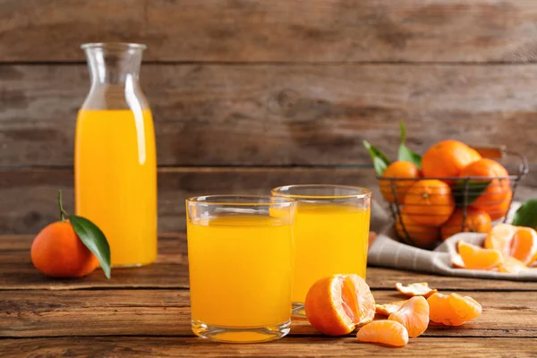 Glasses of fresh tangerine juice and fruits on wooden table — ストック写真