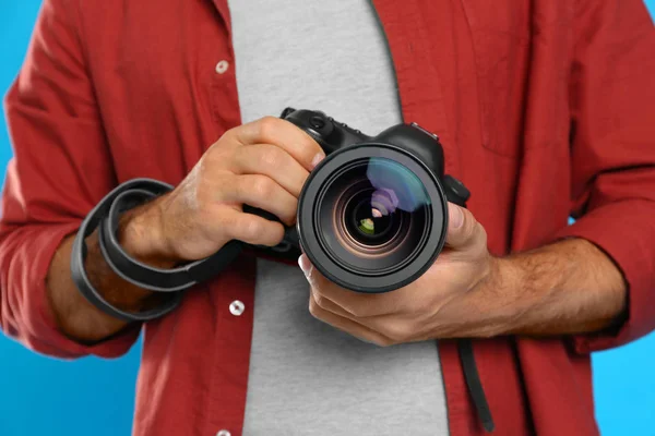 Profesjonalny fotograf pracujący na jasnoniebieskim tle w st — Zdjęcie stockowe