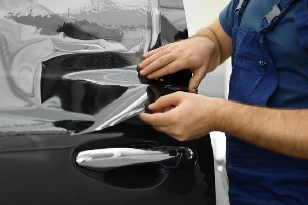 Arbeiter färbt Autoscheibe mit Folie in Werkstatt, Nahaufnahme — Stockfoto