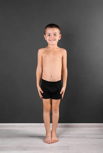 Schattig jongetje in ondergoed nabij donkere muur — Stockfoto