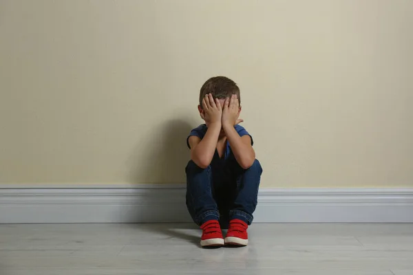 Mały Chłopiec Zamykający Twarz Dłońmi Podłodze Przy Żółtej Ścianie Dziecko — Zdjęcie stockowe